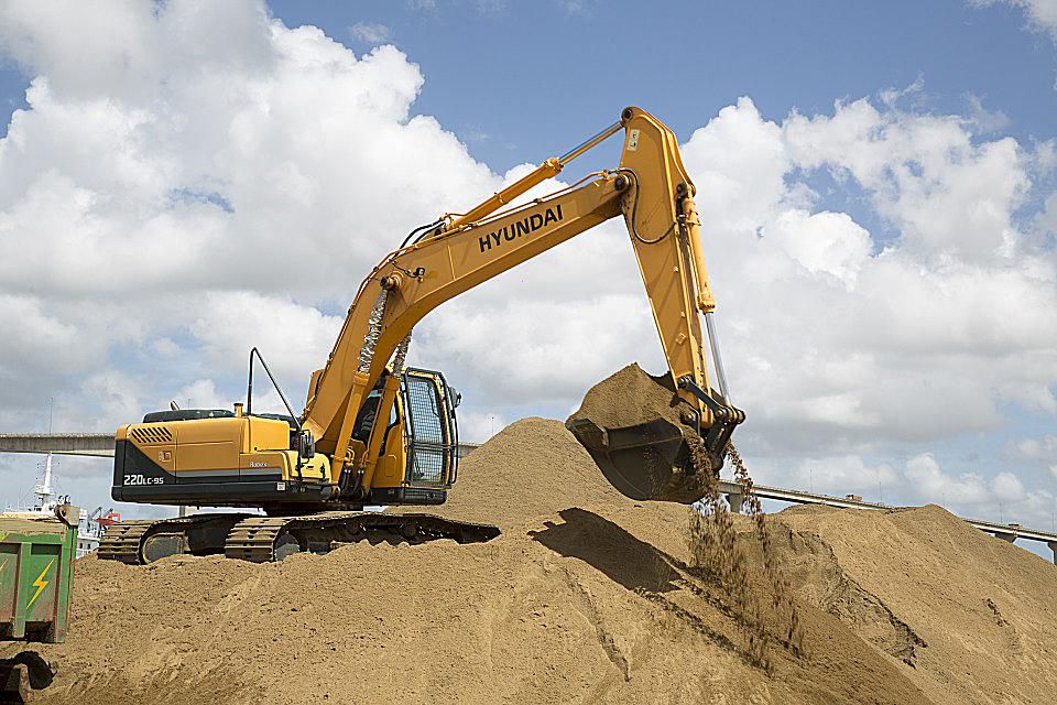 Site supervisor reviewing drawings in front of a bulldozer and steel frame structure