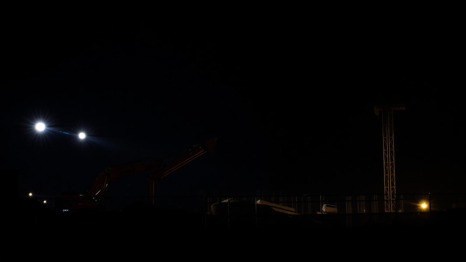 Construction site under floodlights at night