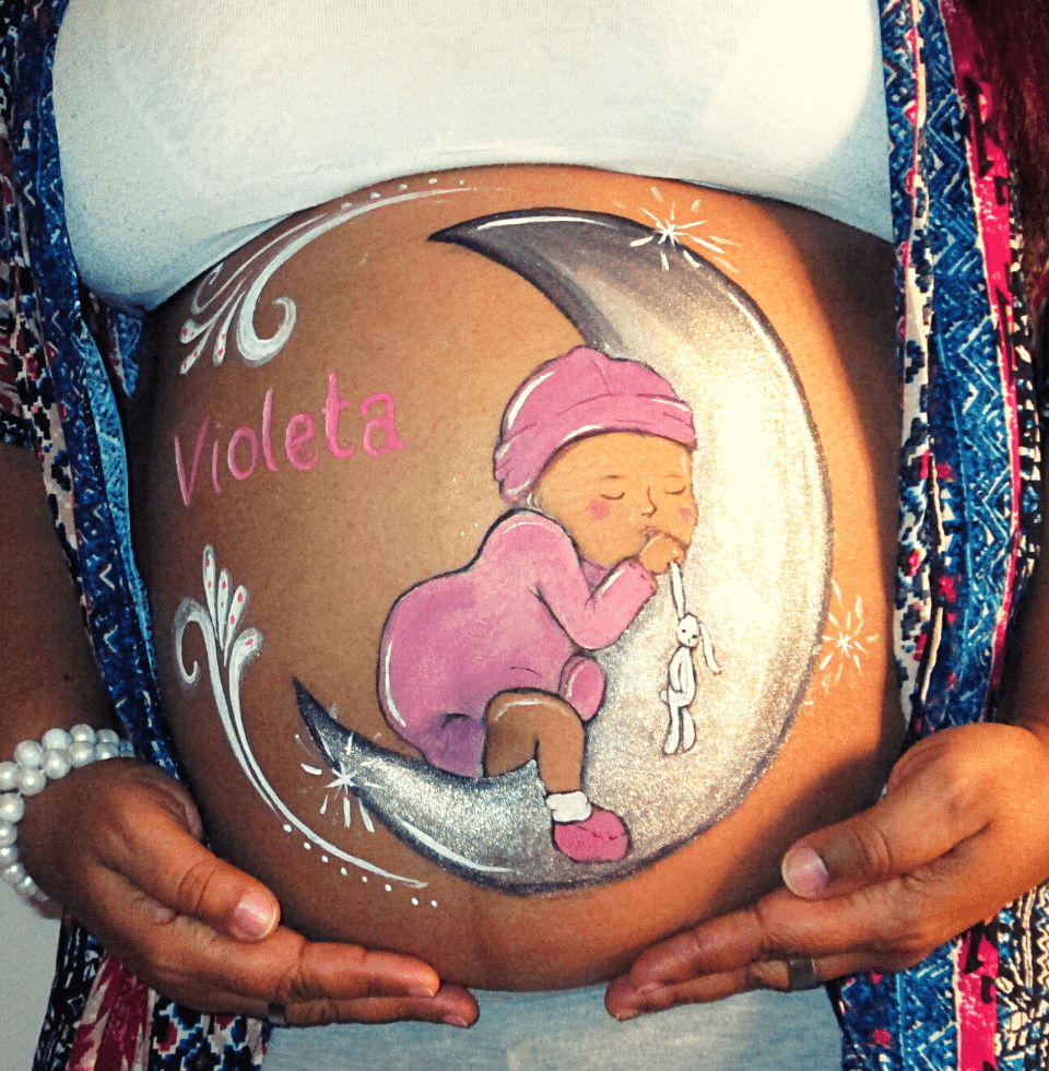 Artista de pintura corporal pintando sobre el vientre de una mujer  embarazada feliz