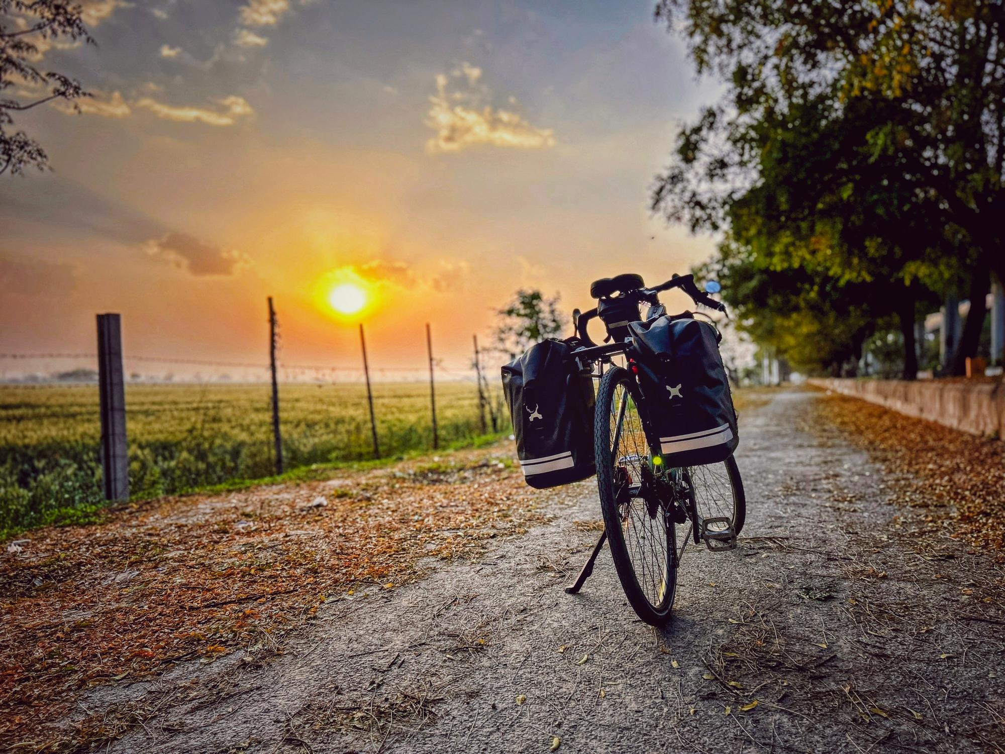 A loaded bicycle at sunrise on a gravel path