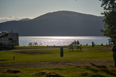 A peaceful beautiful evening over Loch Lomond shores, with silhouettes of people enjoying the scene