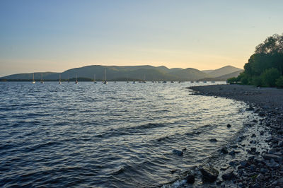 Loch Lomond - Discover the mesmerizing allure of coastal serenity as boats gracefully glide through the expansive waters, while adventurous souls embrace the thrill of rocky shores.