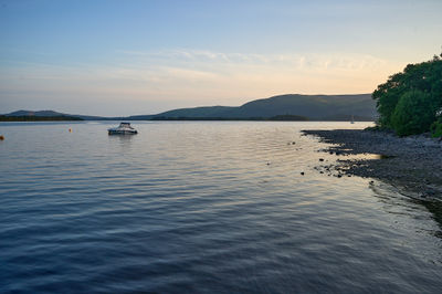 Loch Lomond - Tranquil sunset scene with a boat peacefully sailing on serene water, embraced by fading light and complemented by a playful kite.