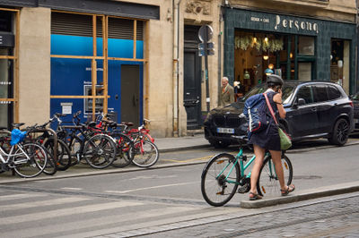 Bordeaux, France, 05.23.2023 Confident woman gracefully pedals through bustling city streets, embodying joy and independence.