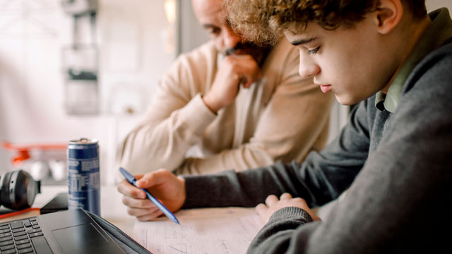 Jongen maakt huiswerk met docent