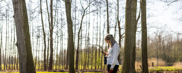 Jongere met hond tussen bomen