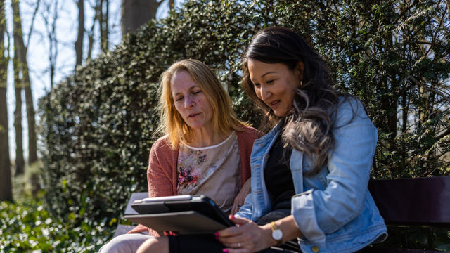 2 vrouwen op tablet bij heg