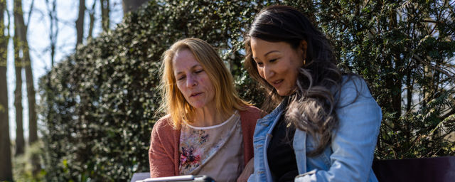 2 vrouwen op tablet bij heg