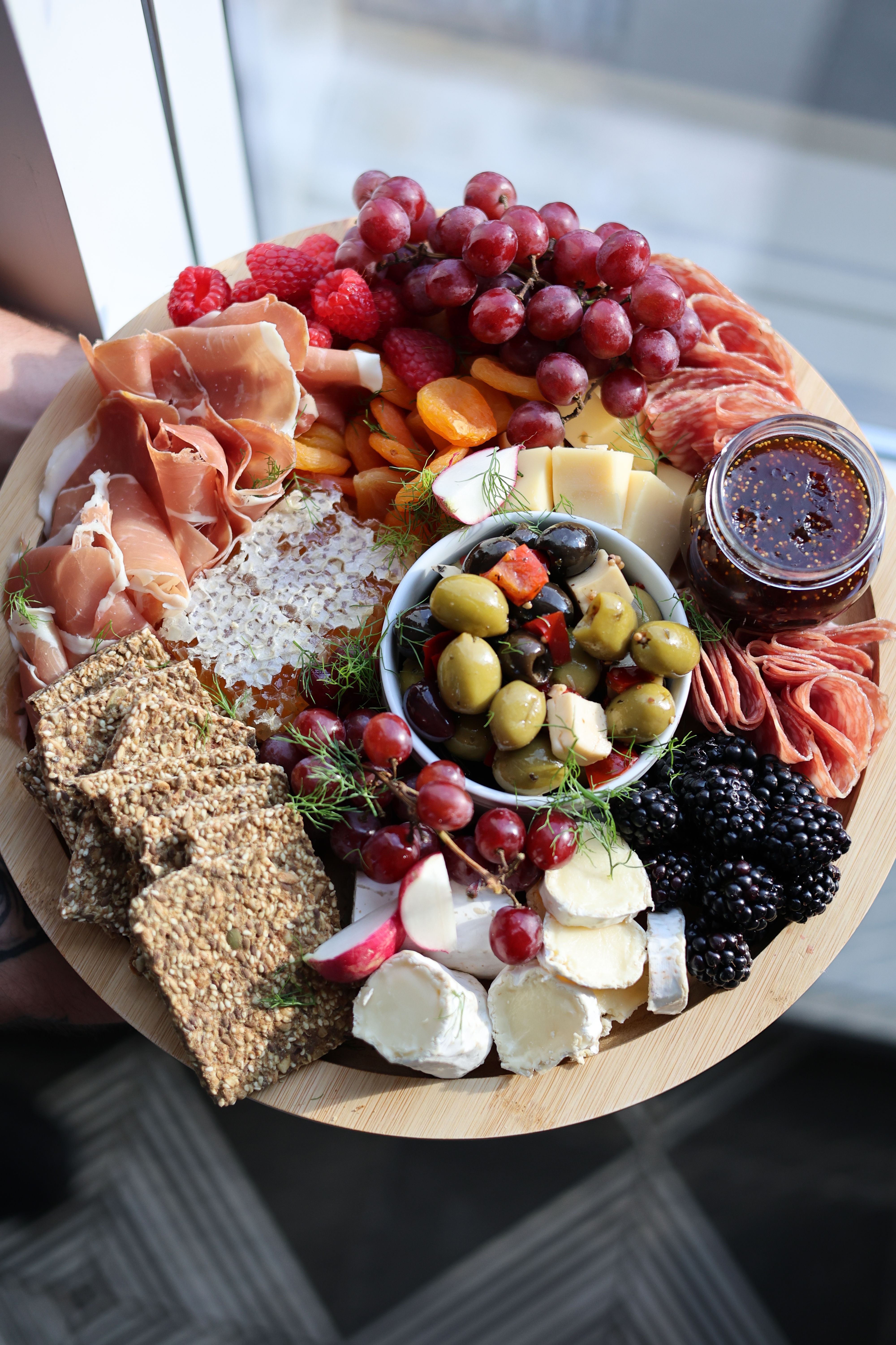 Charcuterie board with cheeses, meats, olives, and seasonal fruit