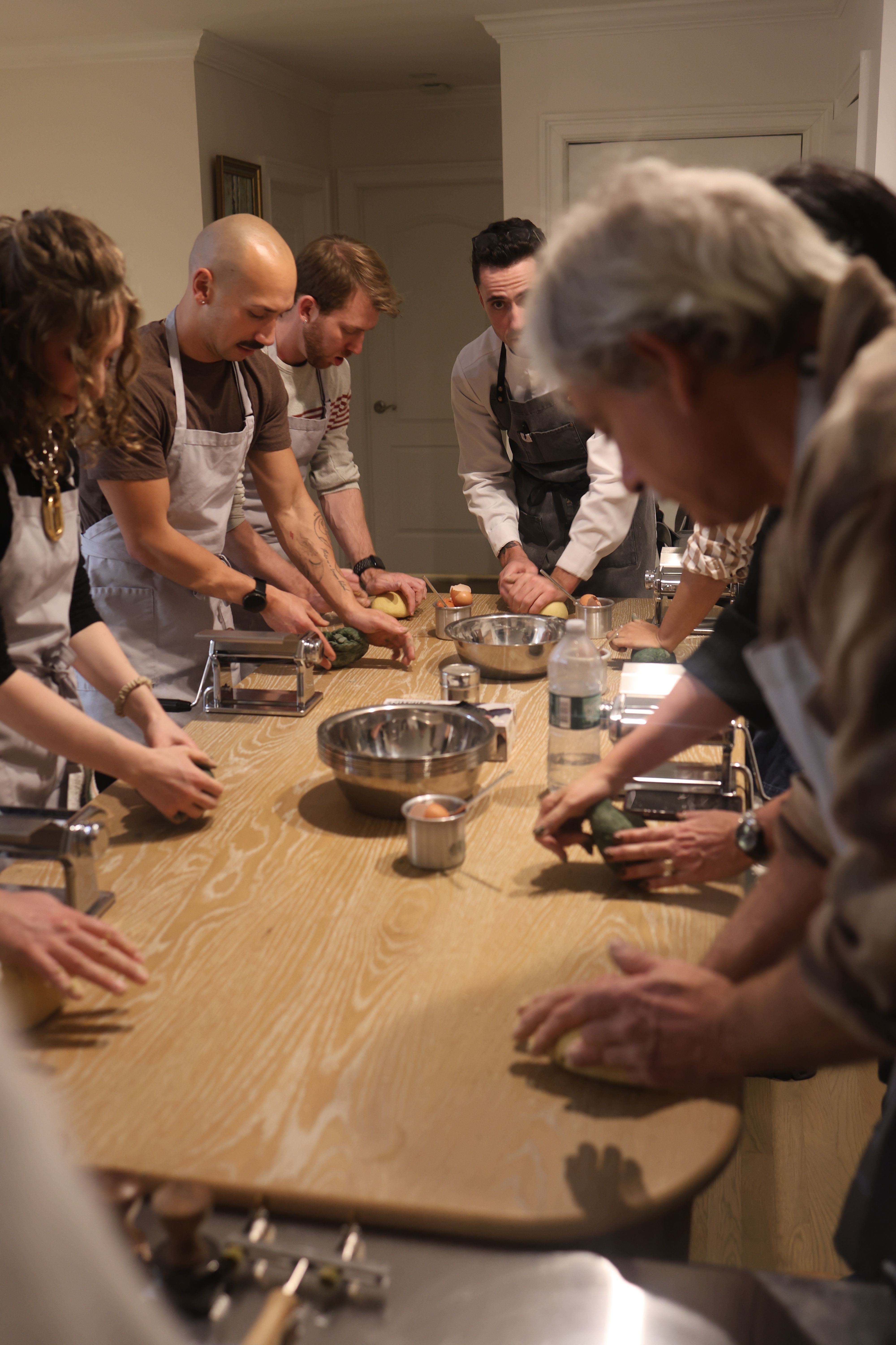 Chef guiding guests through pasta making in a home kitchen