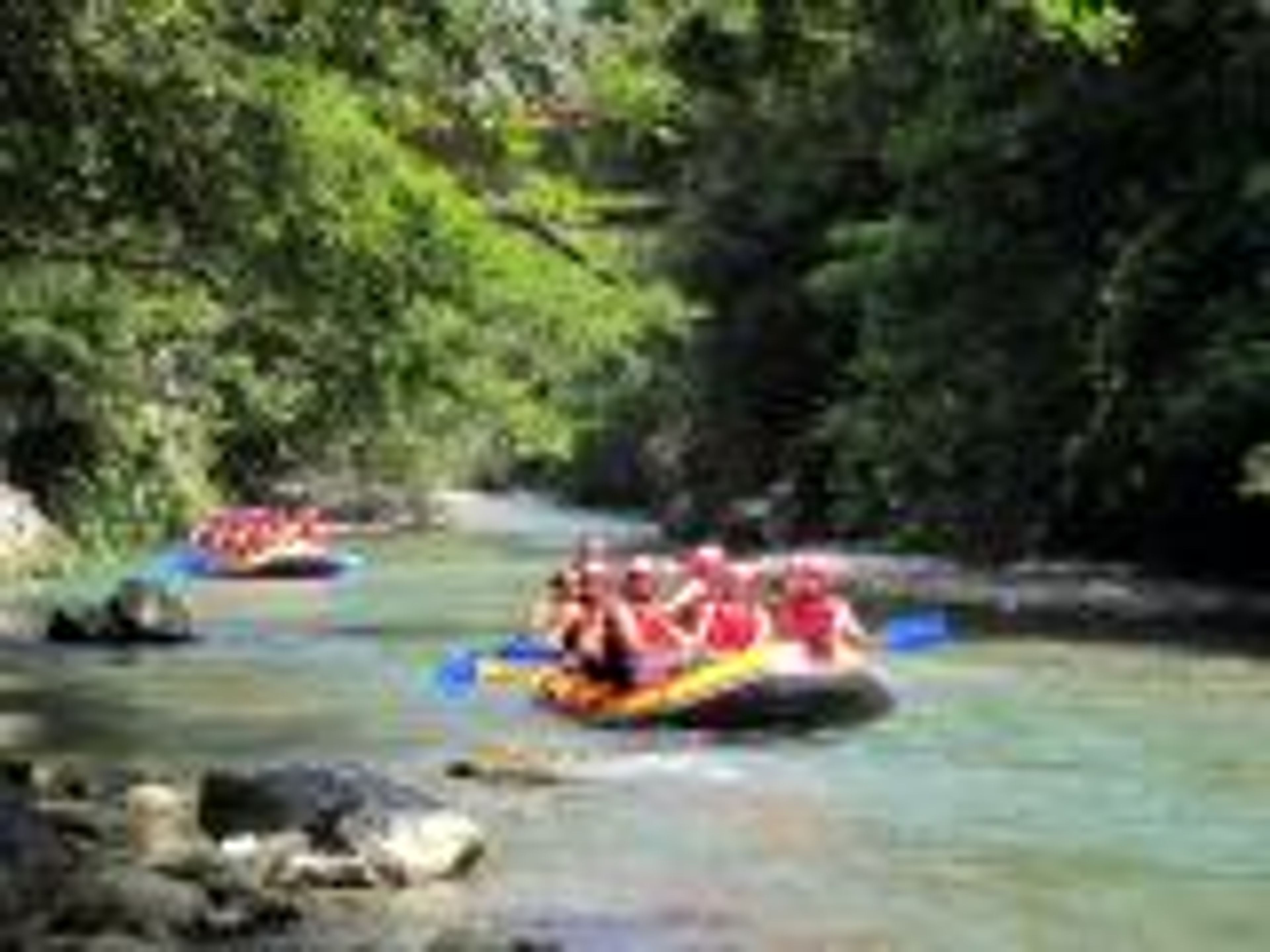 Two rafts navigating a river surrounded by lush greenery.