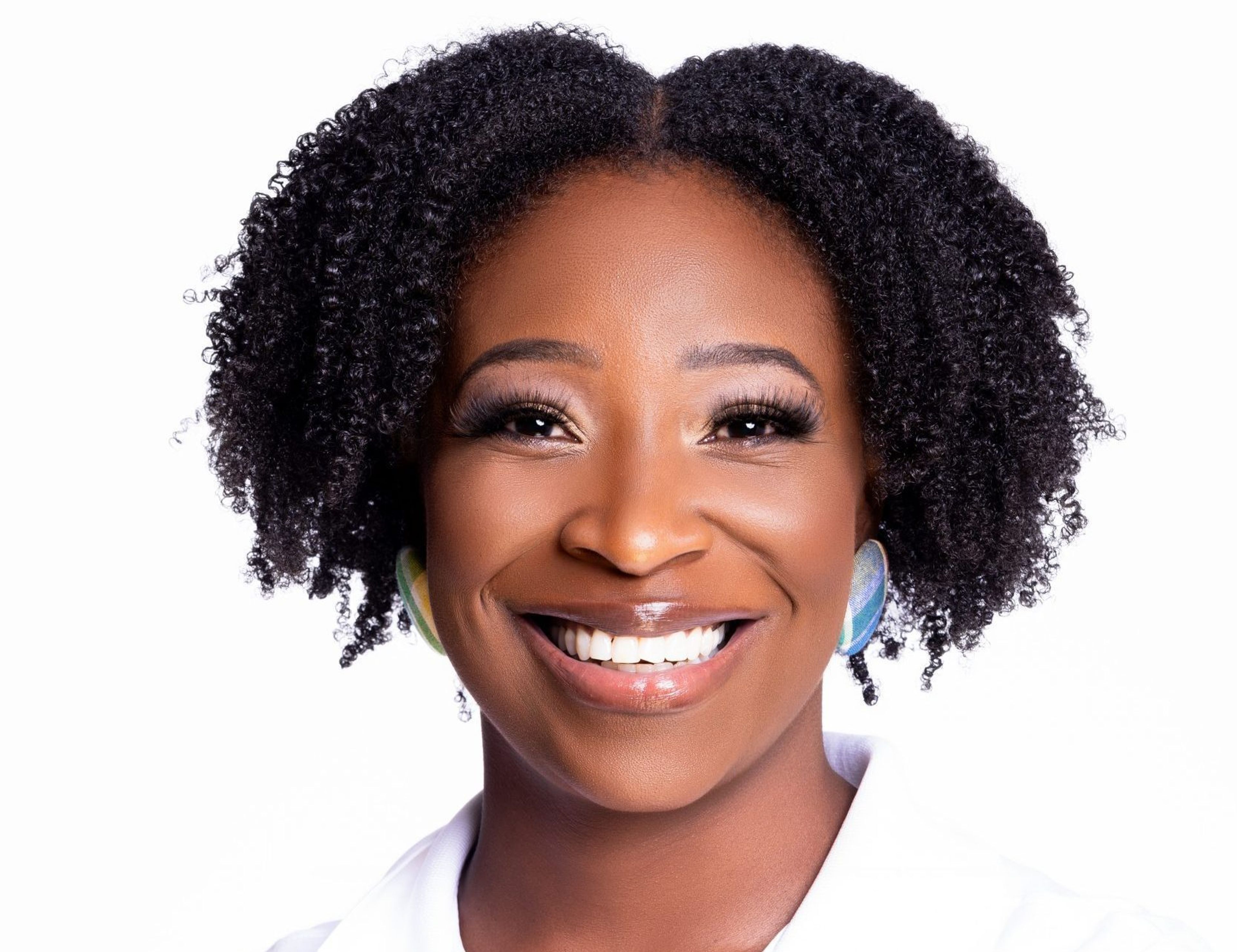 Person with curly hair wearing a white shirt and headphones, face obscured.