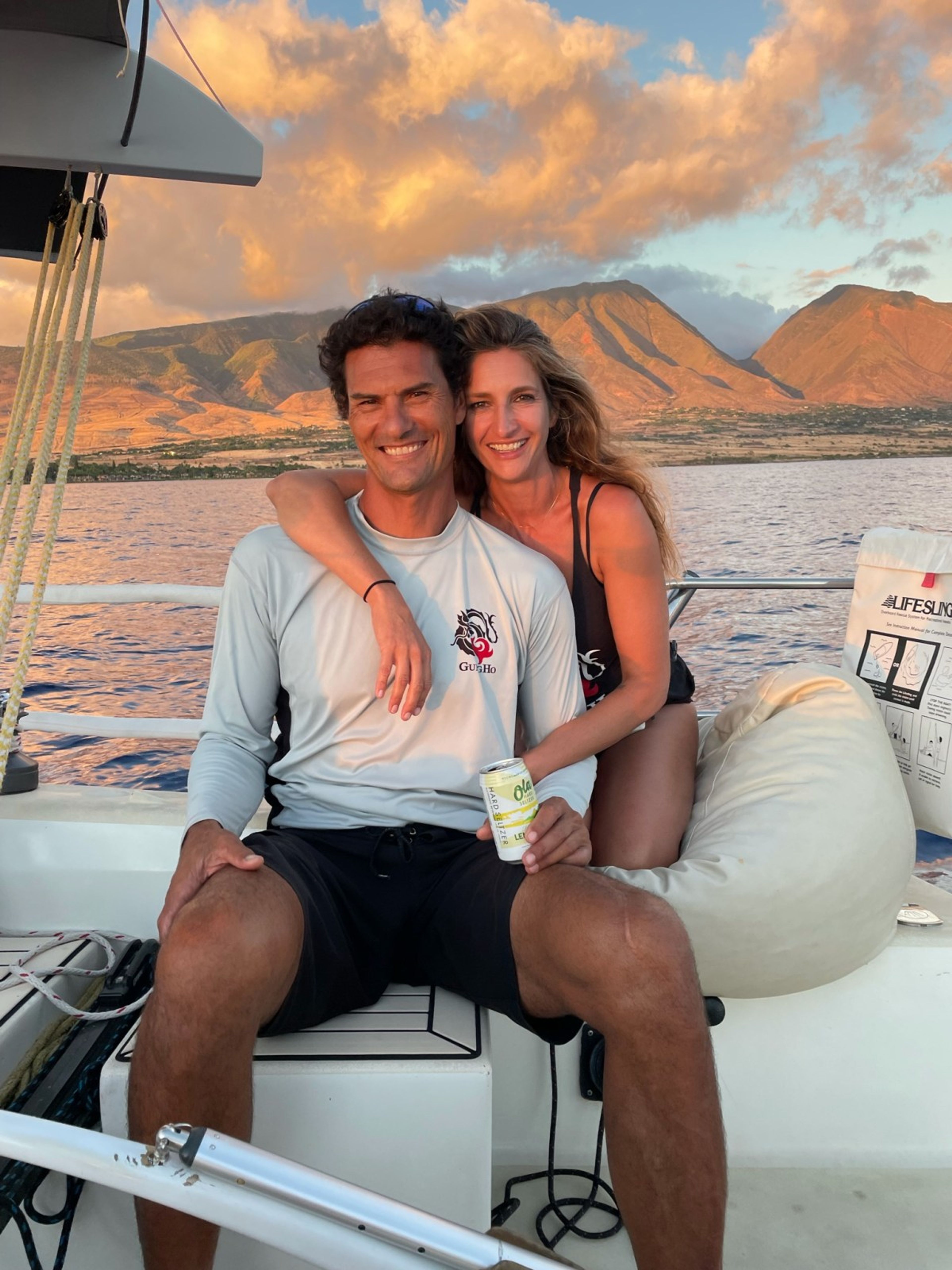 A couple enjoying a sunset on a boat with mountains in the background.