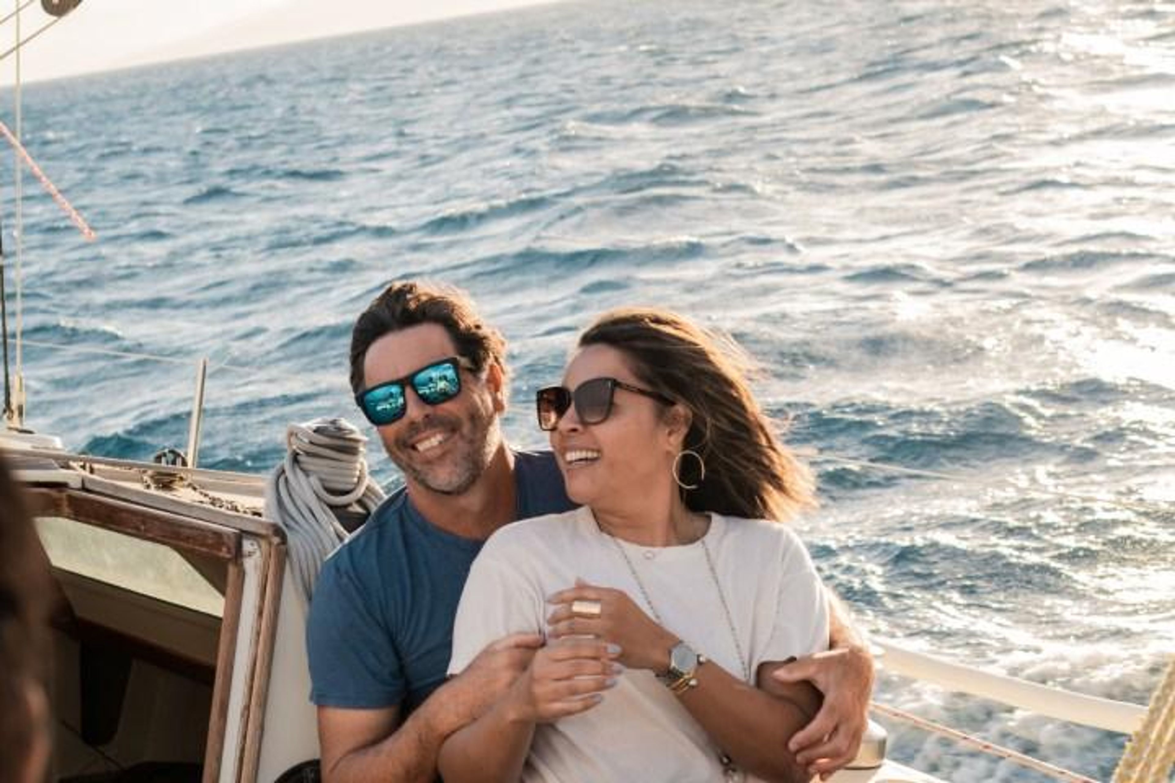 Couple enjoying a sunny day on a boat with the ocean in the background.