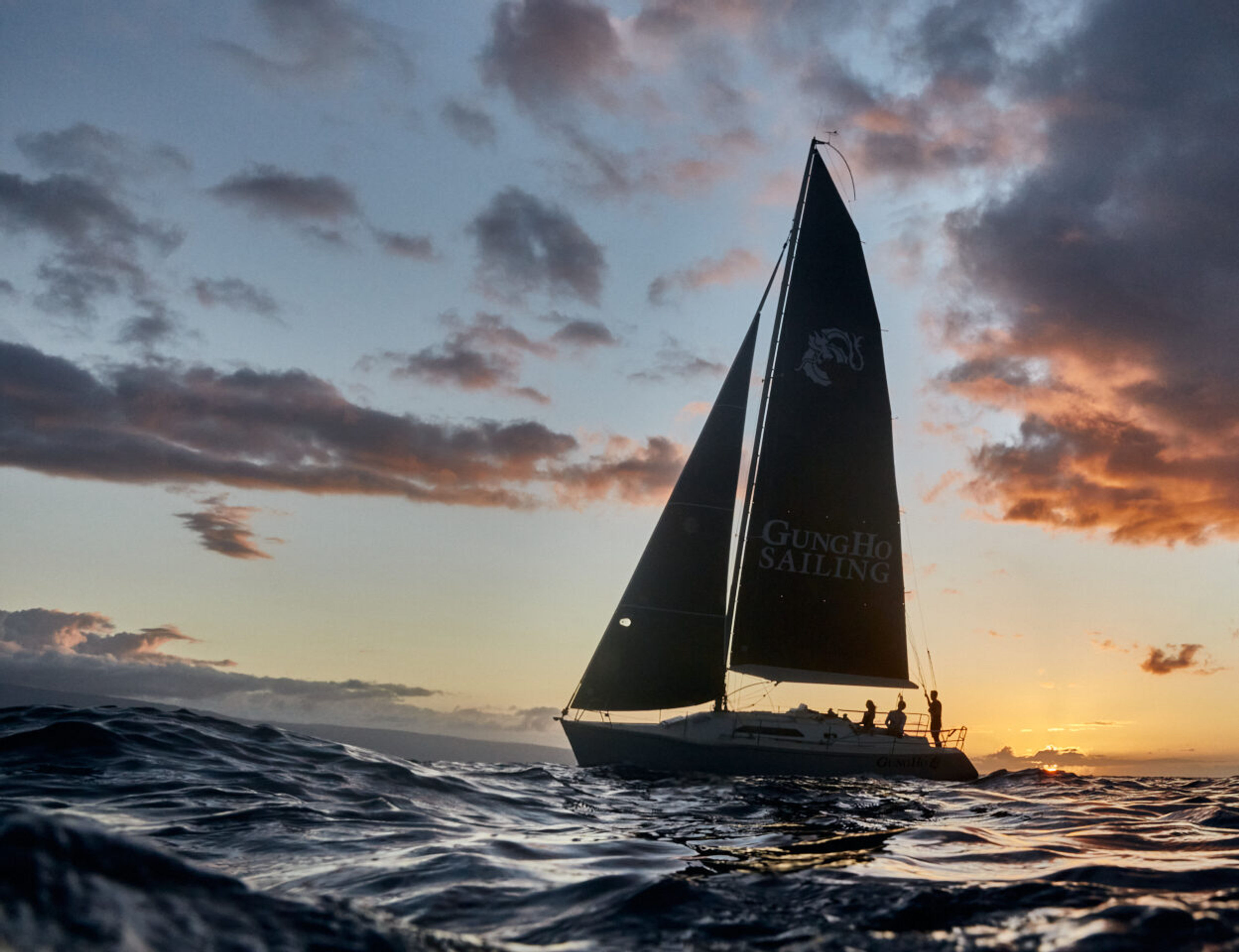 Sailboat with black sails on the ocean during sunset