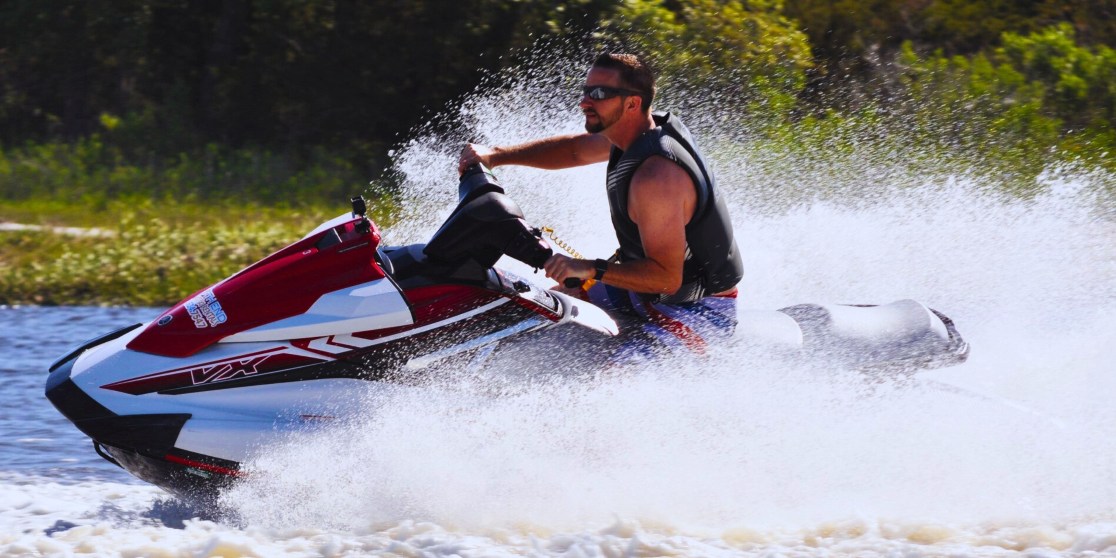 Person riding a jet ski on a waterway with splashes around.