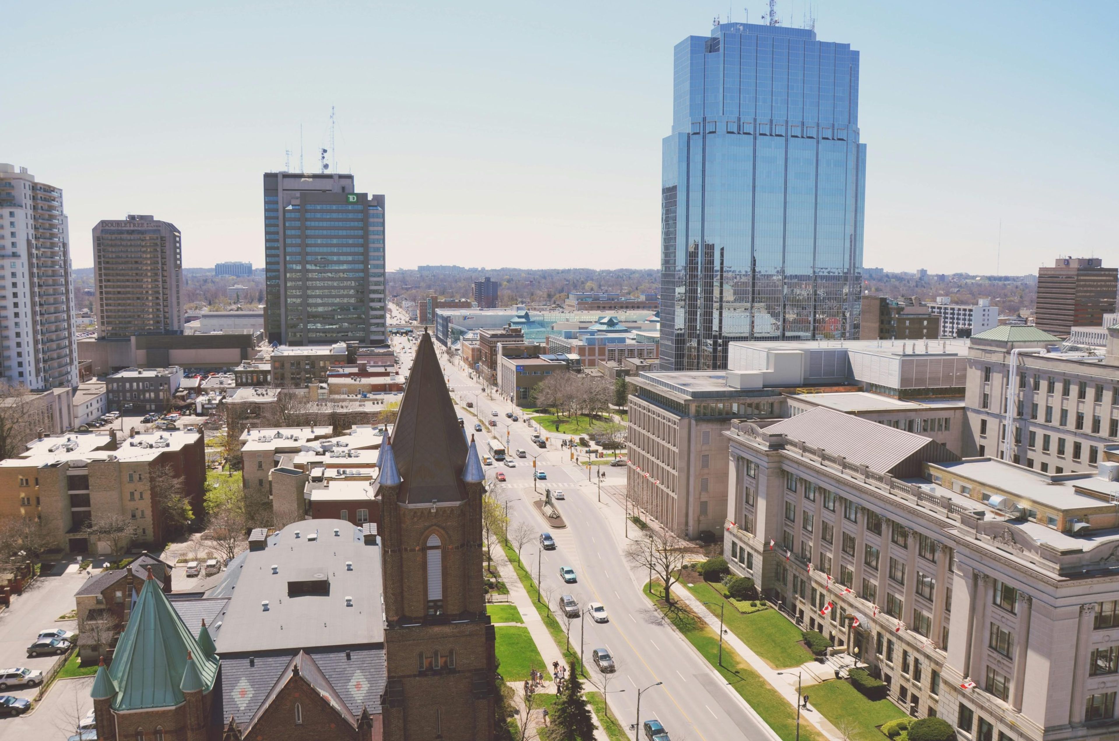 Aerial view of a city with modern buildings and a church steeple in the foreground.