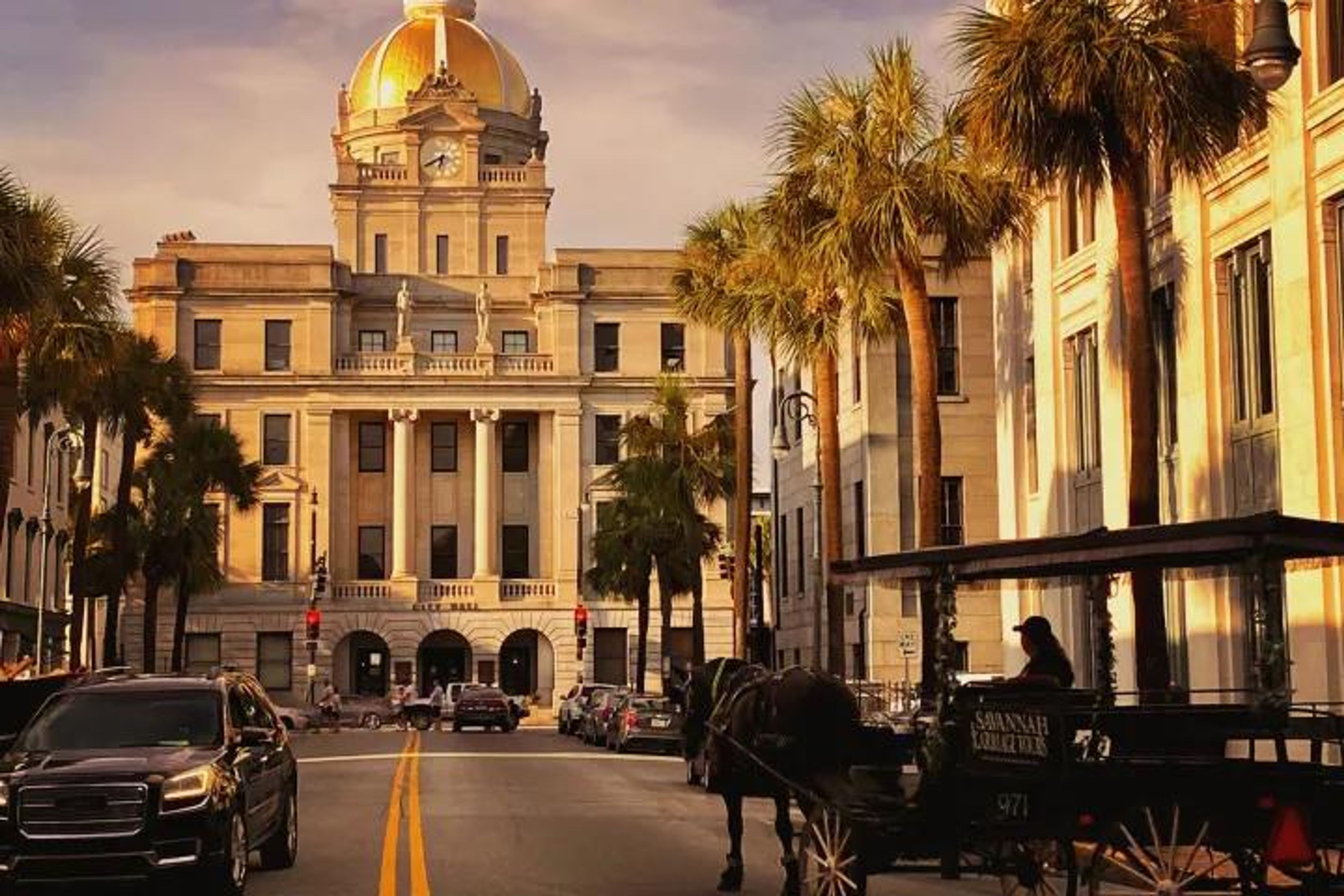 Street view of a historic building with a golden dome and palm trees in Savannah.