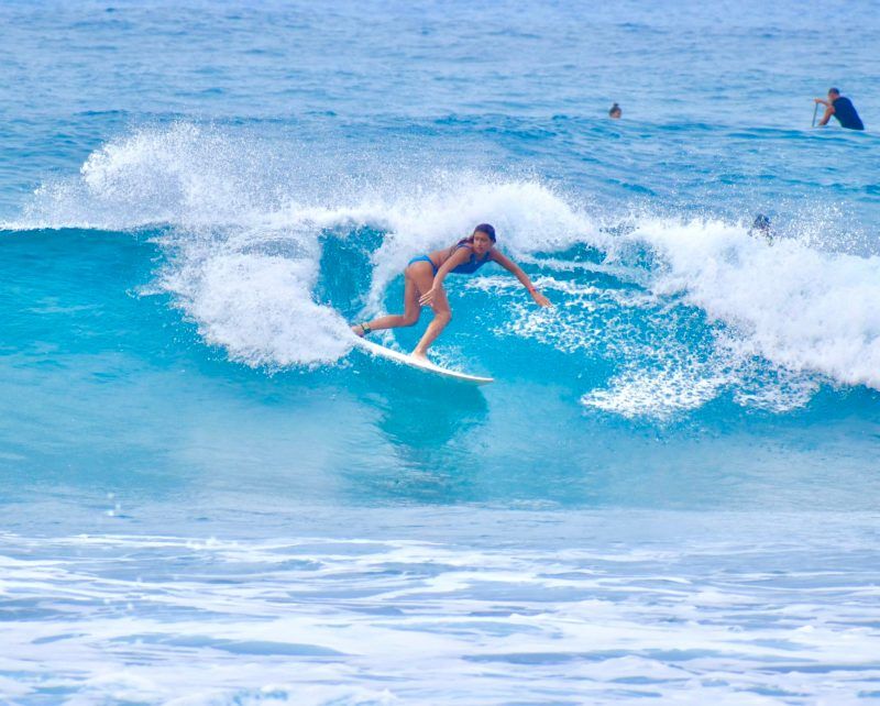 A surfer riding a wave in clear blue water