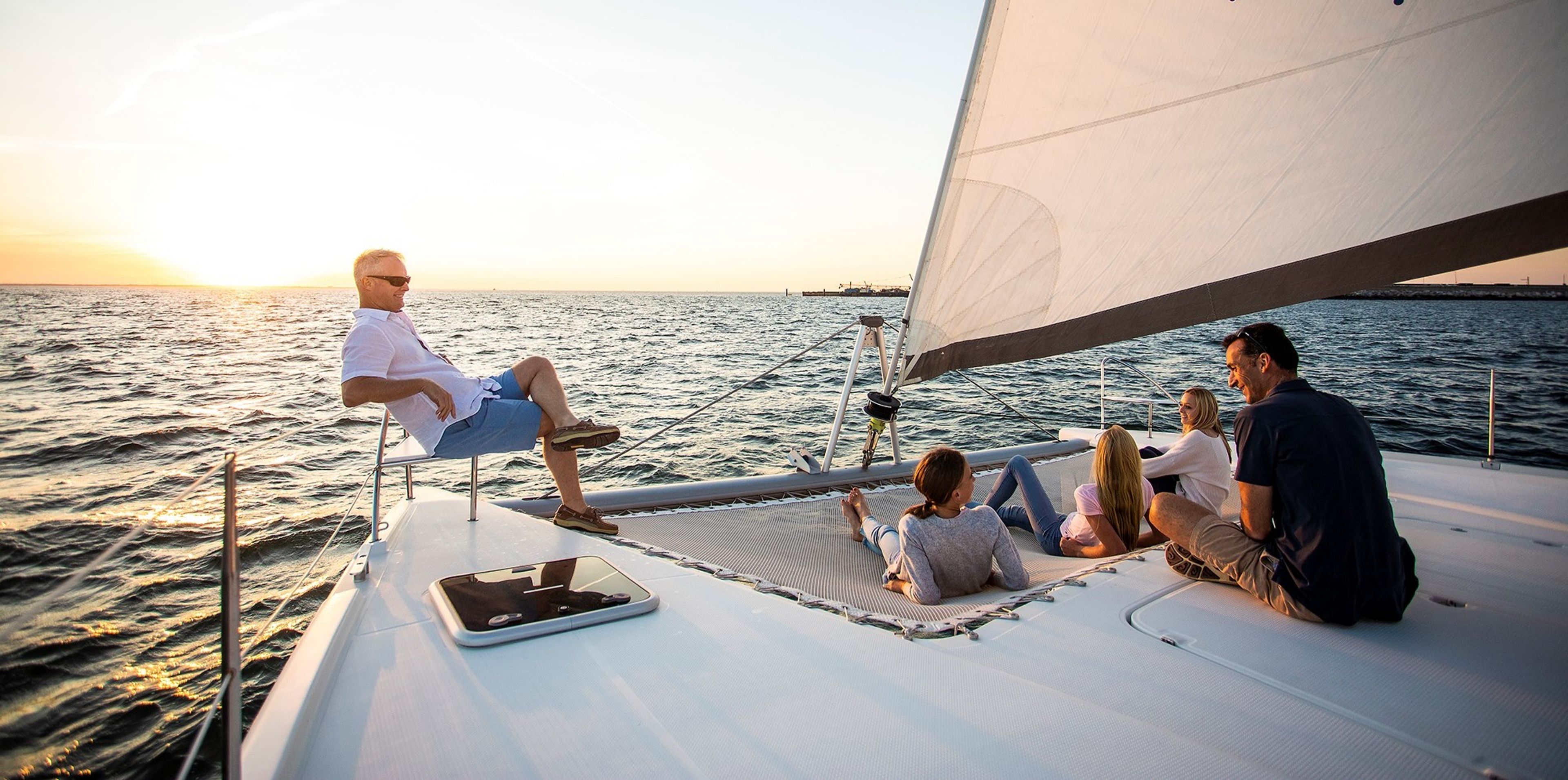 A family enjoying a sunset on a sailboat in the ocean.