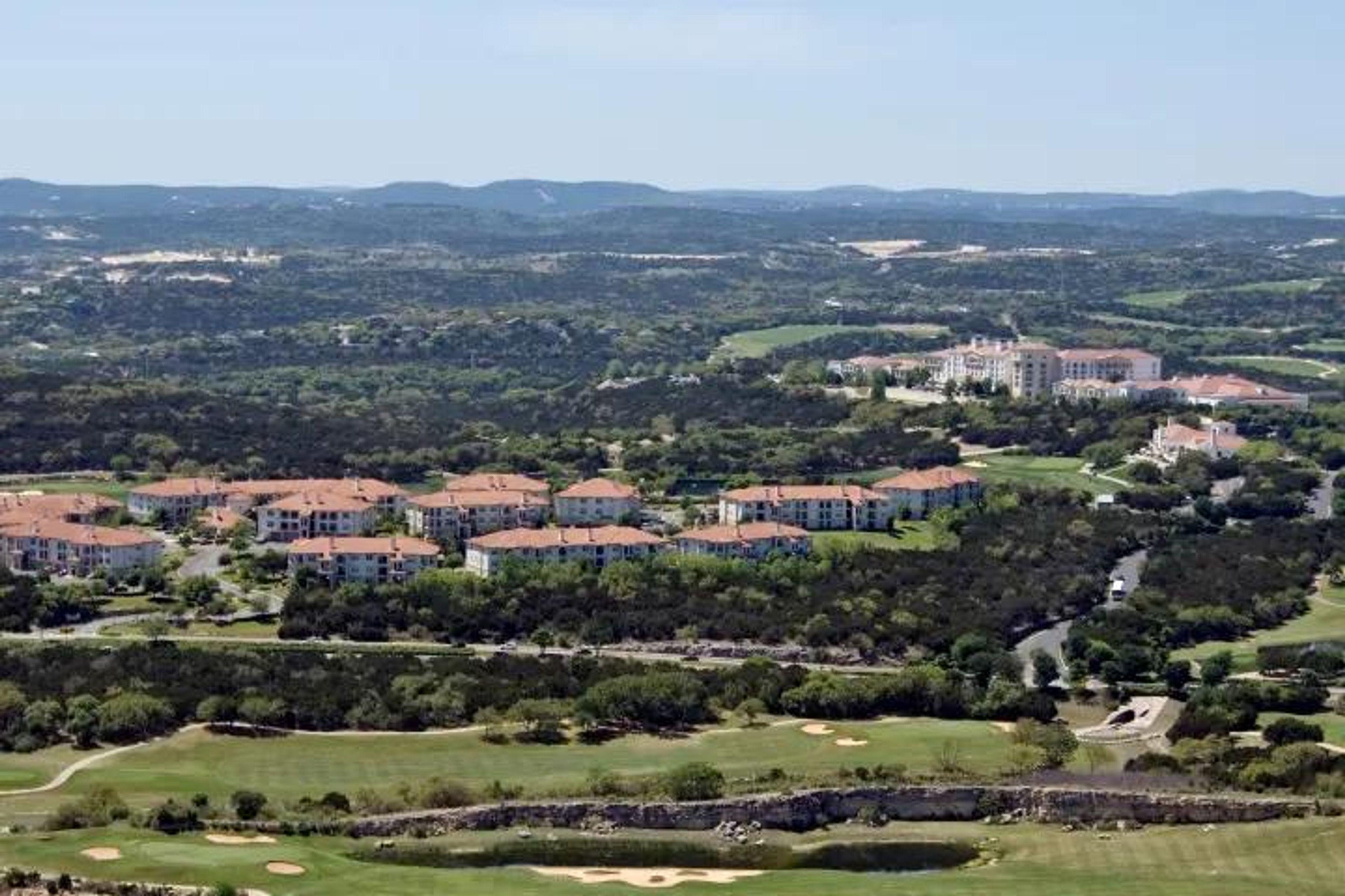 Aerial view of a golf course with residential buildings and green landscapes.