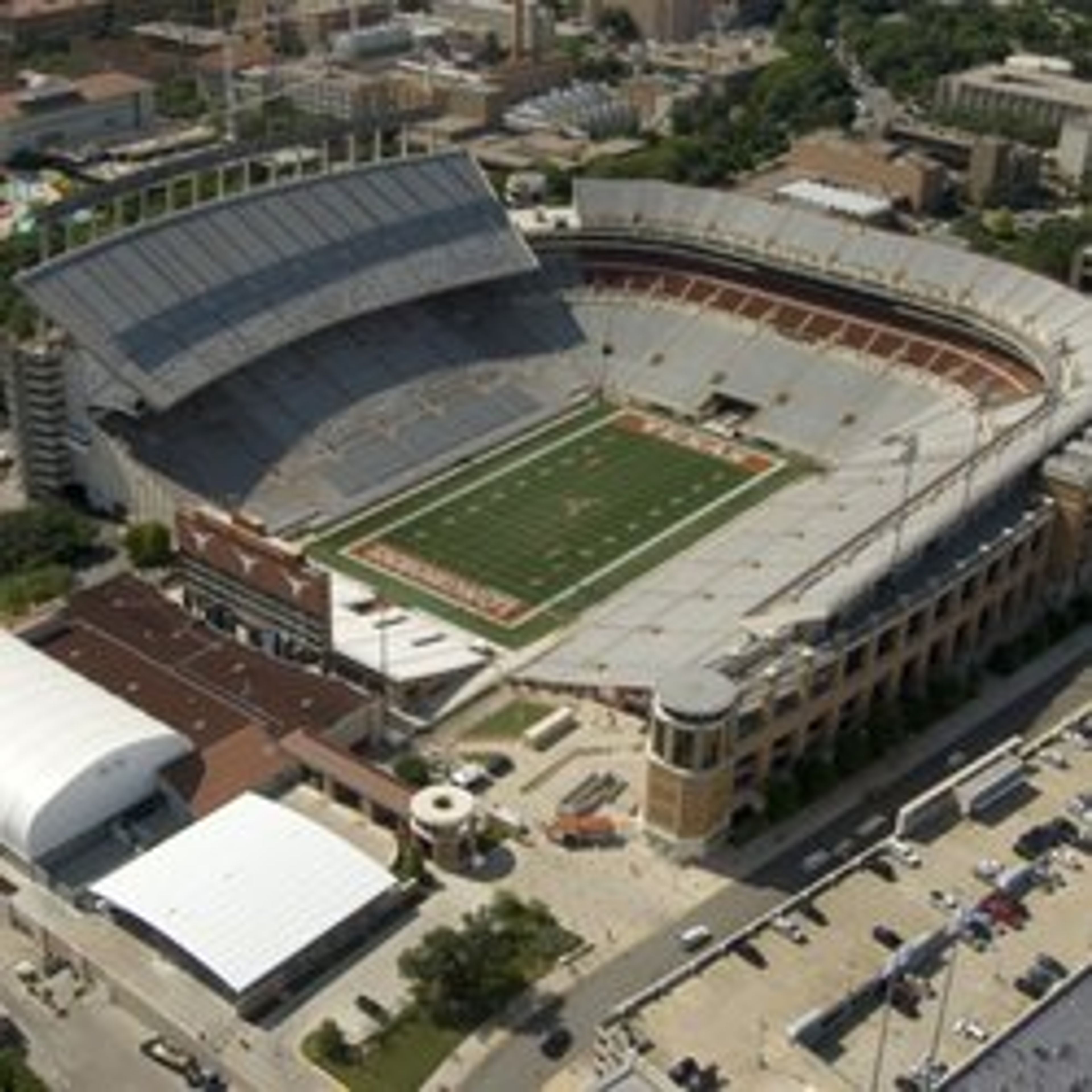 Aerial view of a large stadium with a football field and surrounding buildings.