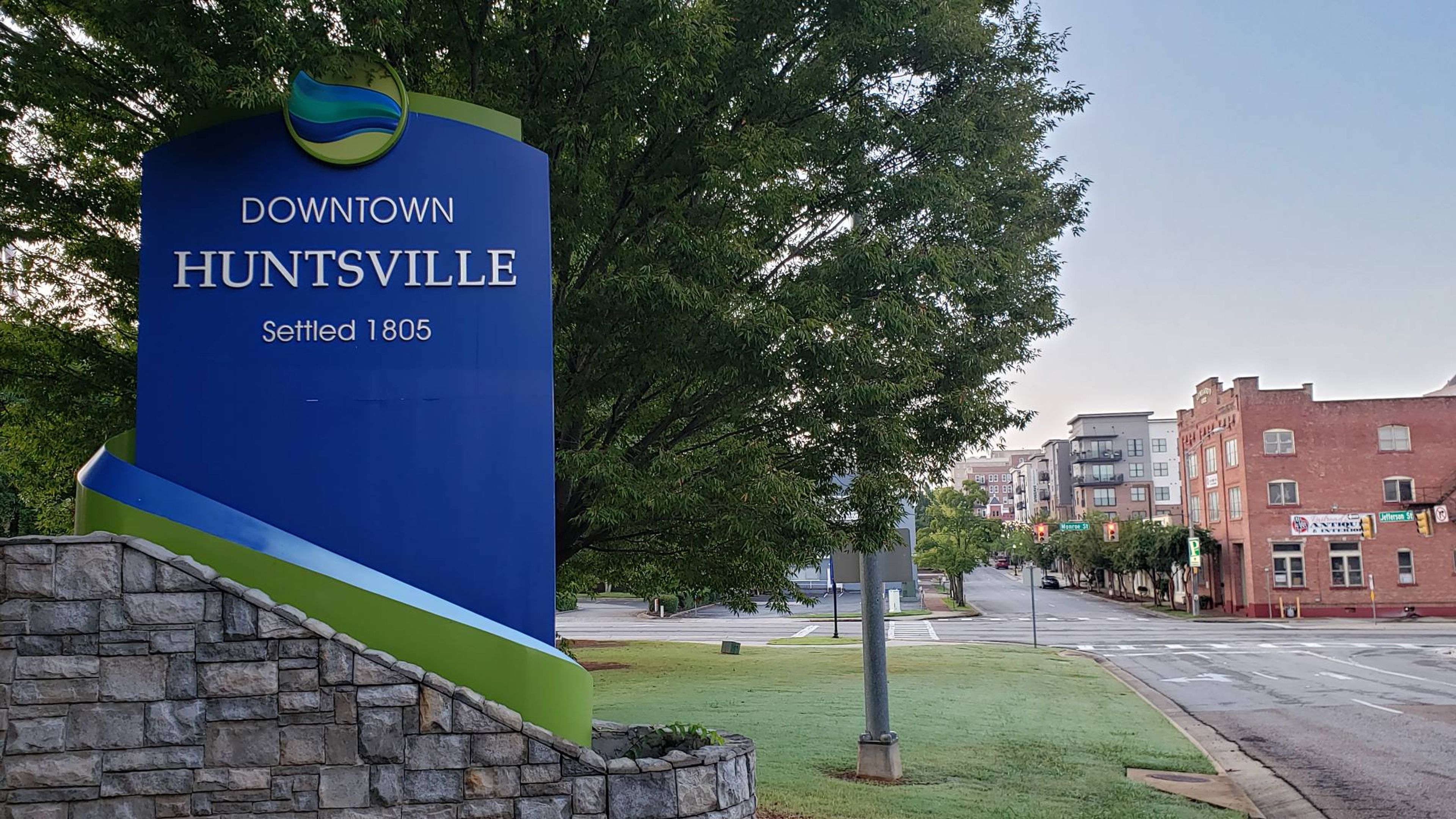 Sign for Downtown Huntsville, Alabama, with trees and buildings in the background.