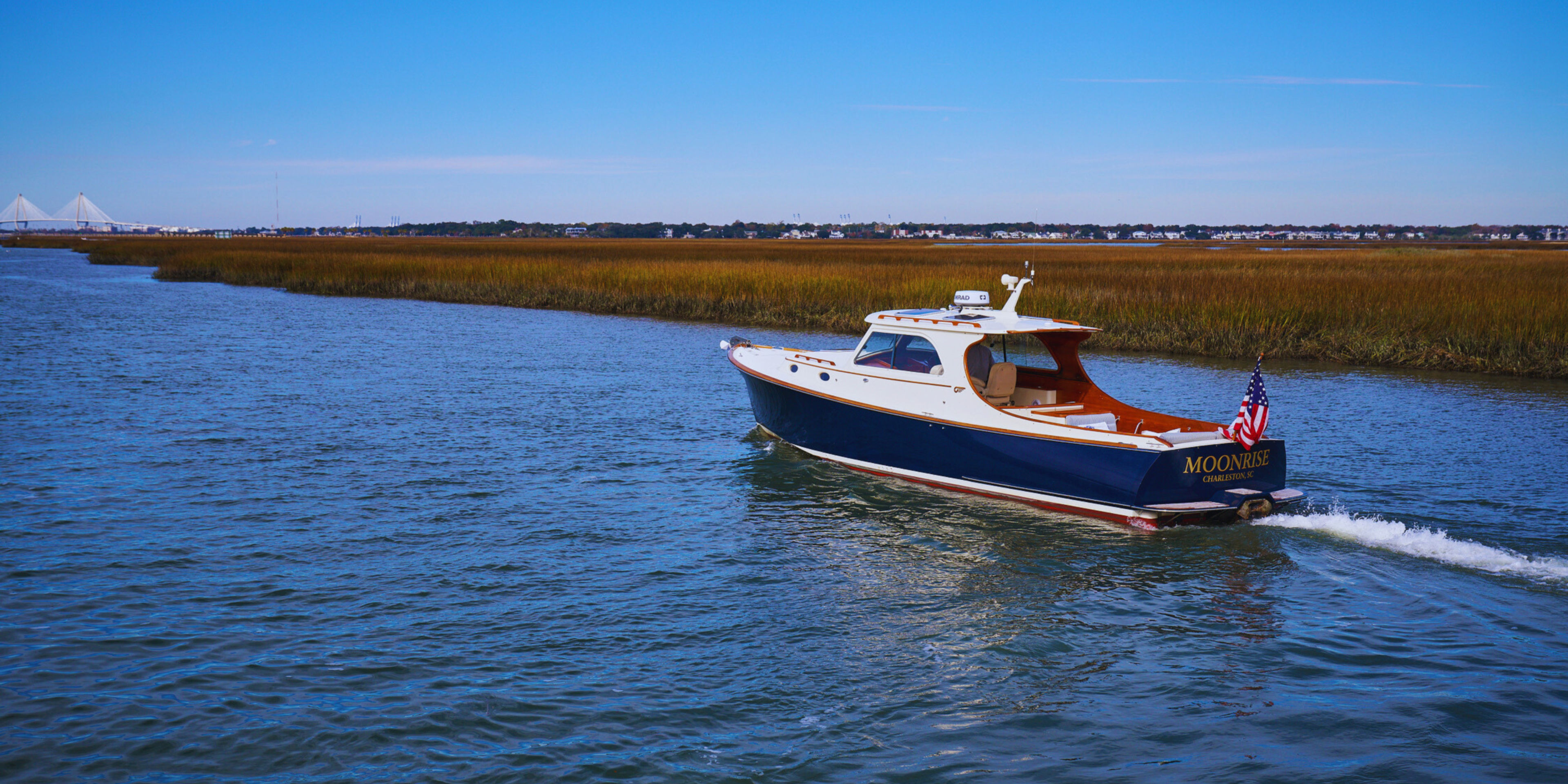 A boat named Moonrise navigates a waterway surrounded by marshland.