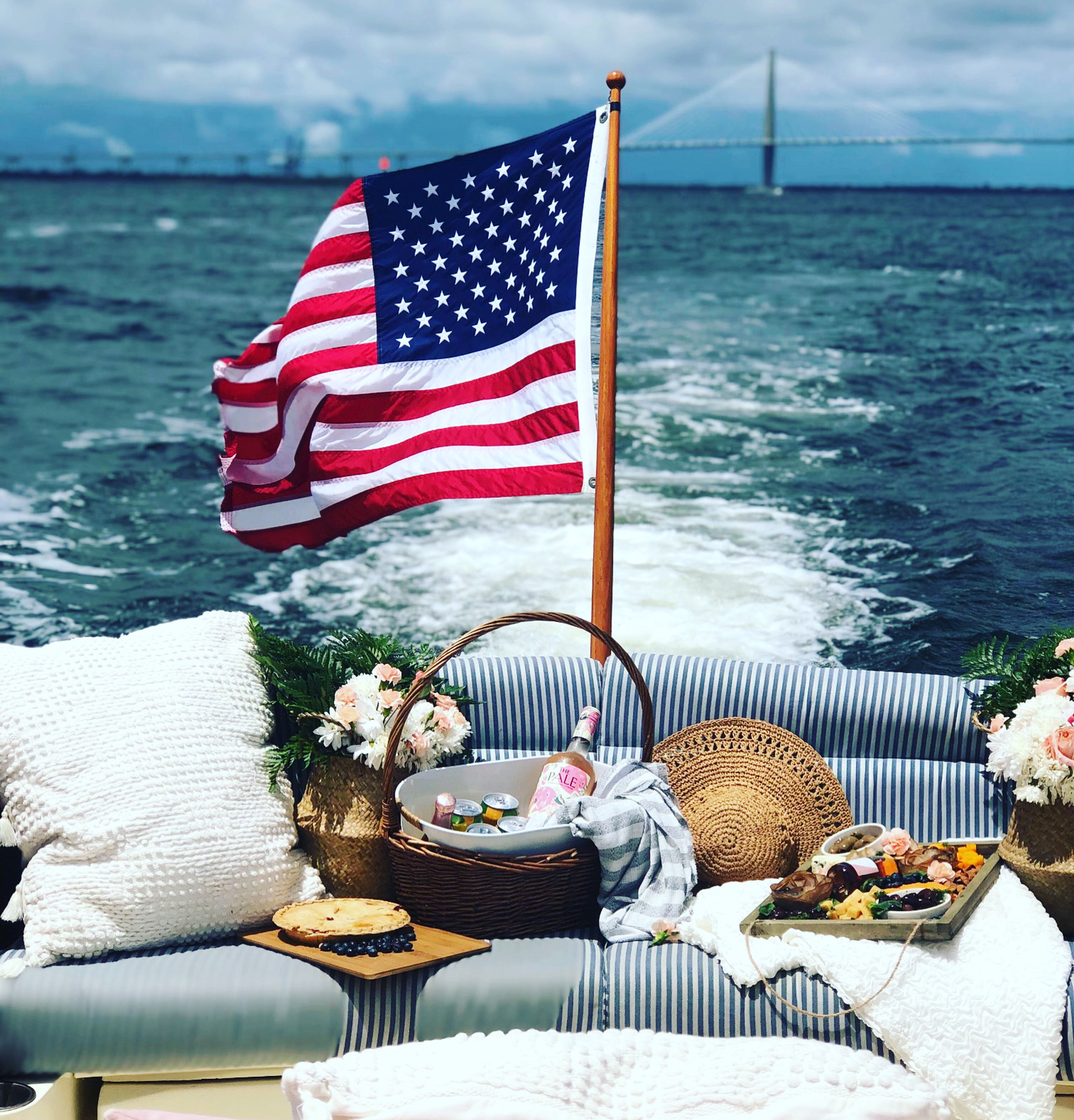 A boat with an American flag, picnic setup, and a bridge in the background.