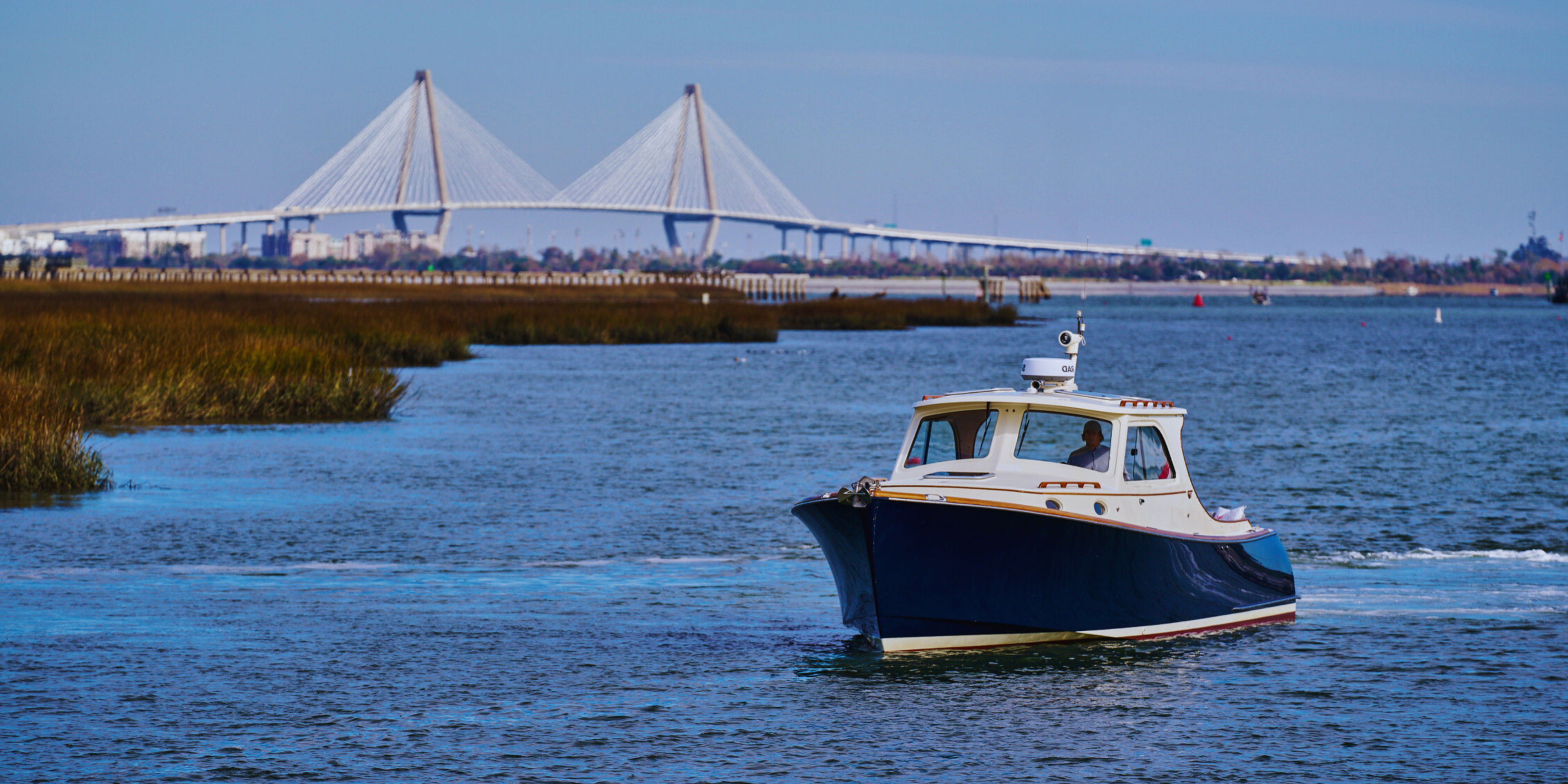 A boat navigating a waterway with a bridge in the background.