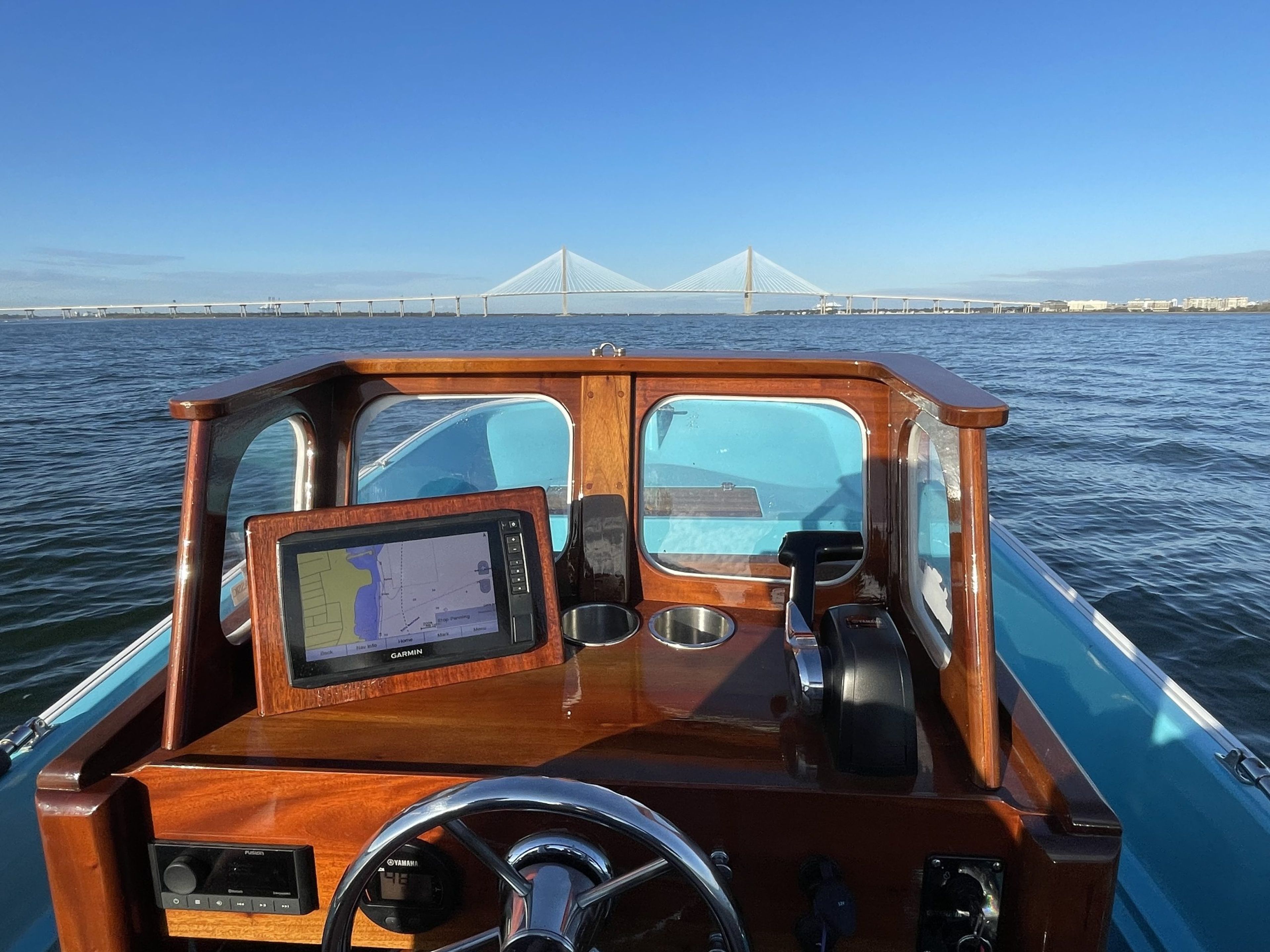 View from the helm of a boat with a bridge in the background and a navigation screen.