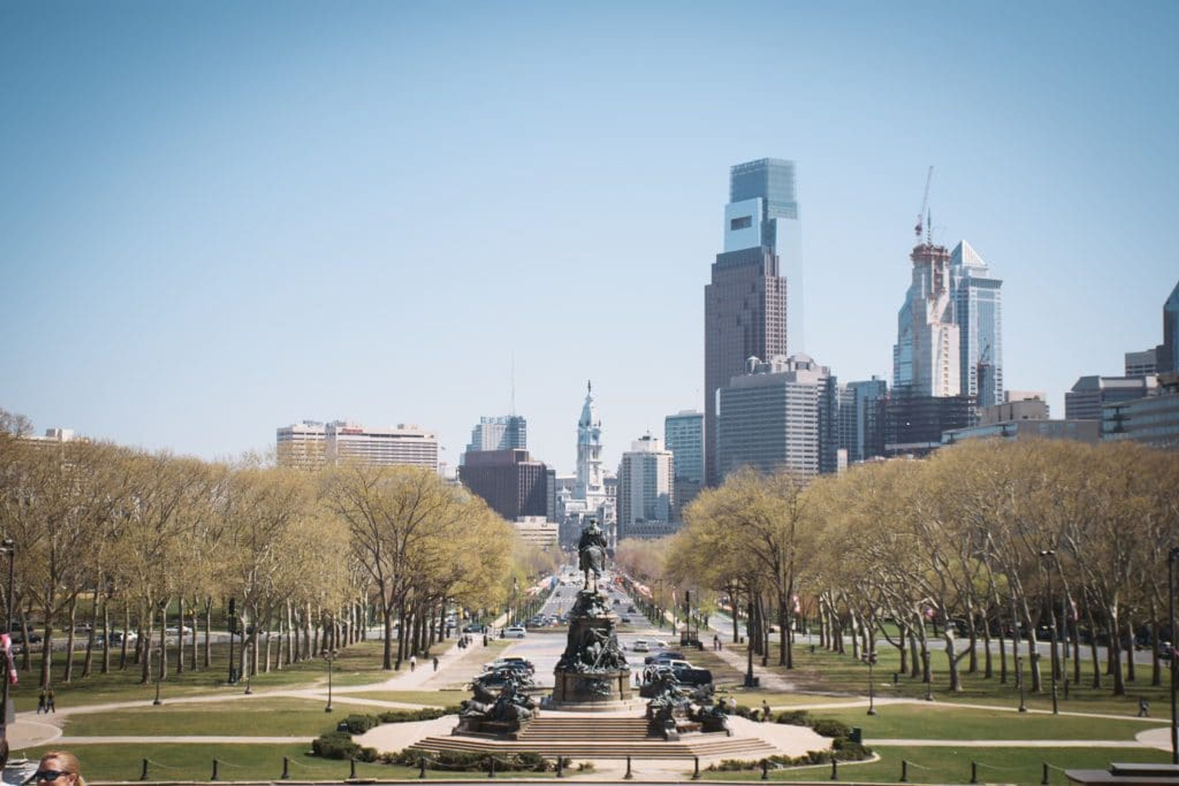 View of Philadelphia skyline with trees and park in the foreground.