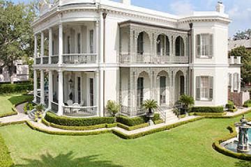 Expansive mansion with lots of lacy ironwork attached to the facade.