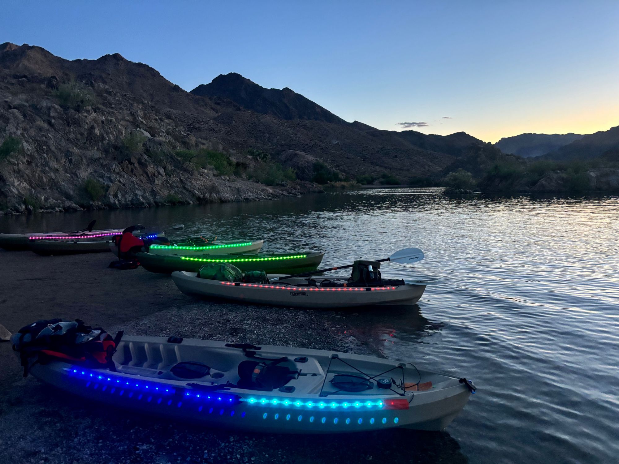 Illuminated kayaks glowing on the Colorado River during twilight near Emerald Cave