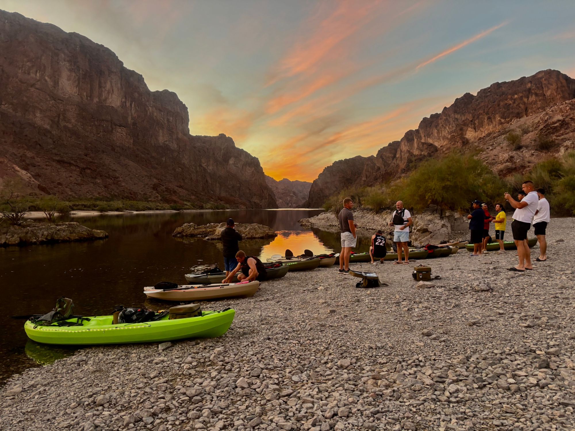 Kayakers pause at a beach to enjoy the sunset