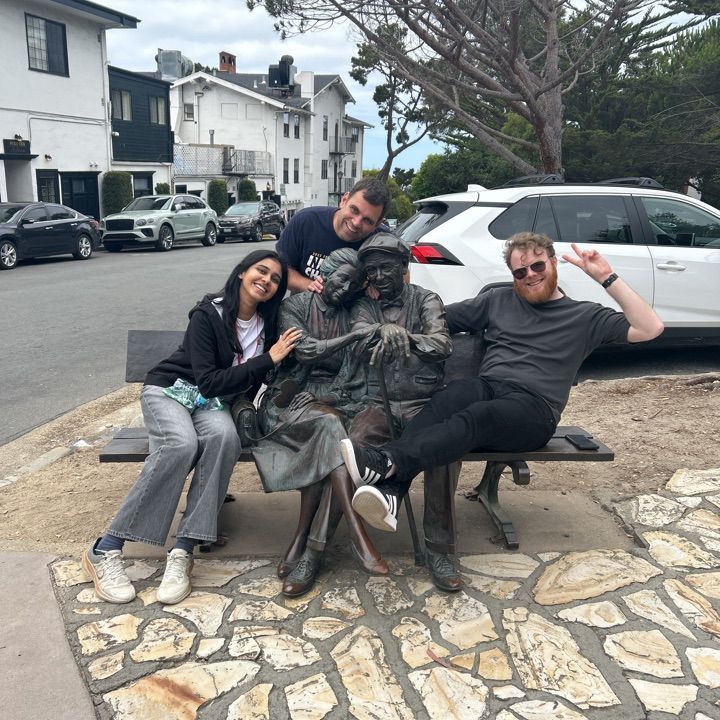 Two men and a woman pose with a sculpture in Carmel by the Sea