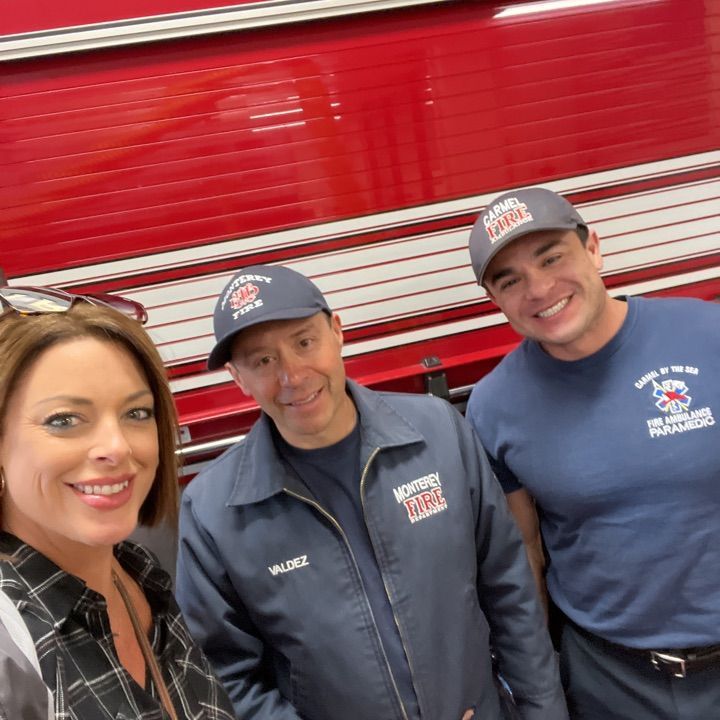 A woman poses with two firefighters