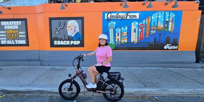 Cyclists posing beside a colorful mural in San Antonio&rsquo;s D.R.E.A.M. District.