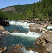 A view up river of a kayaker coming through the rapids
