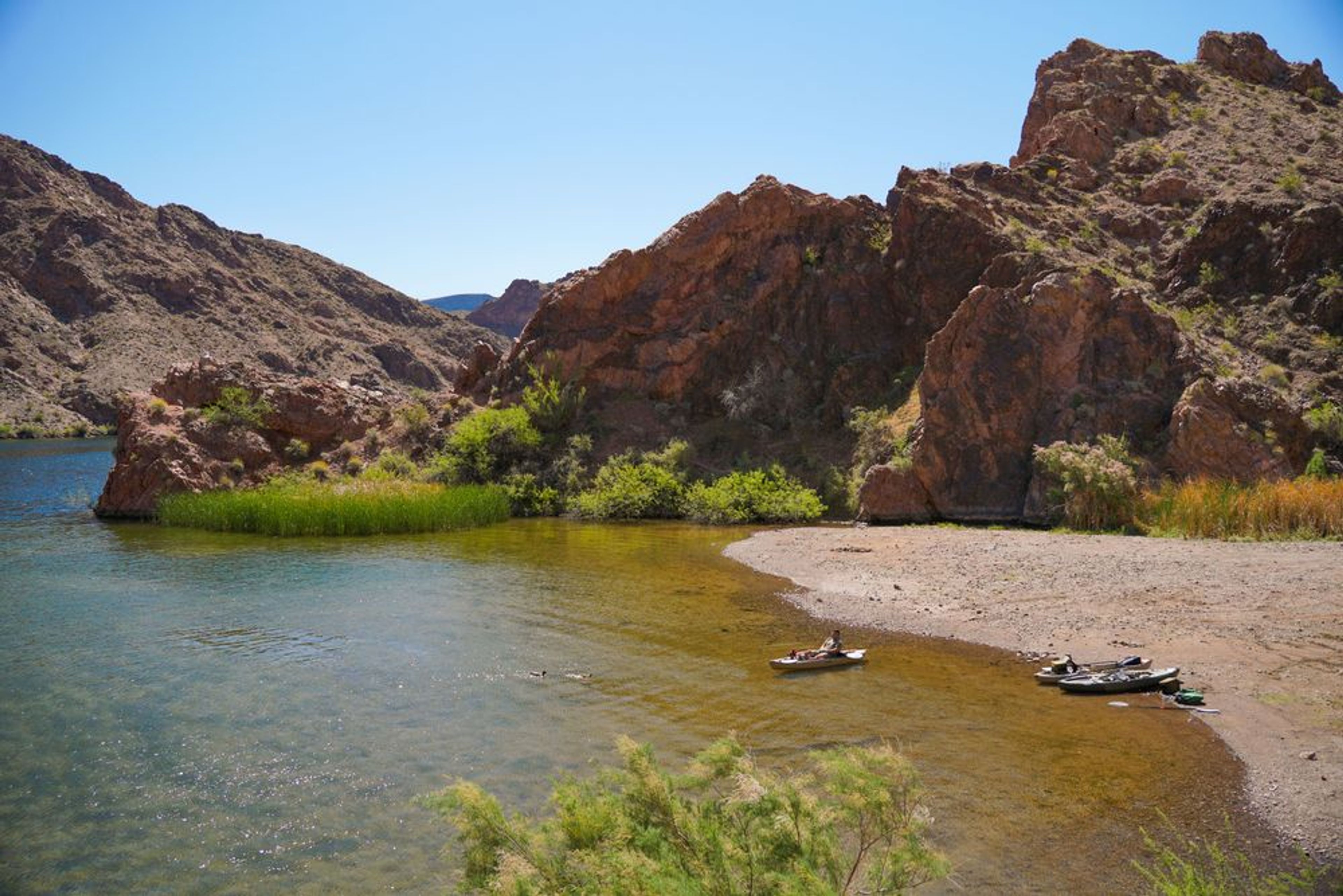 Kayaker resting on a secluded beach on the Colorado River during a full-day ancient river kayak tour, near Las Vegas