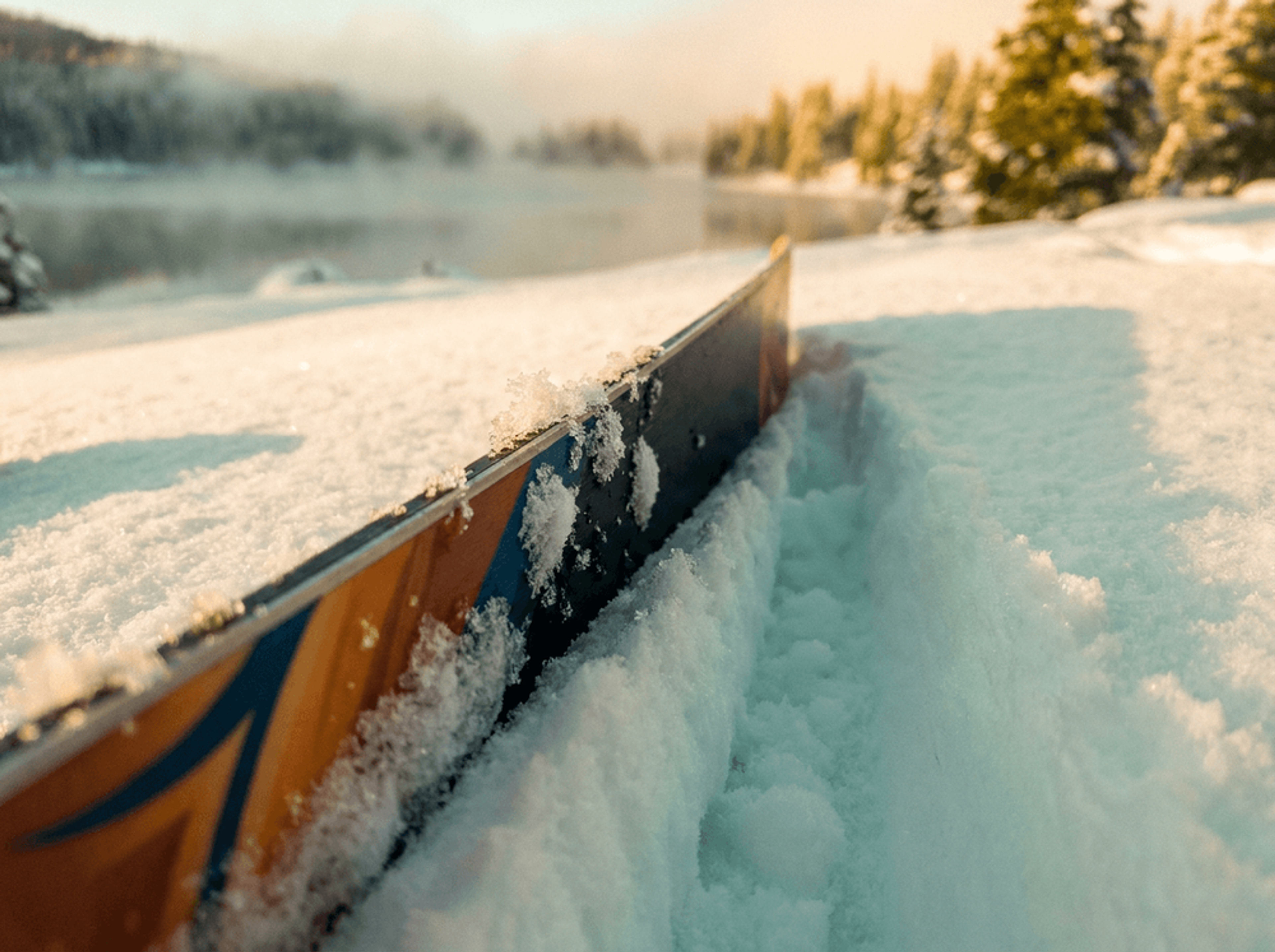 Close-up of ski edges cutting through fresh powder snow showing detailed snow texture