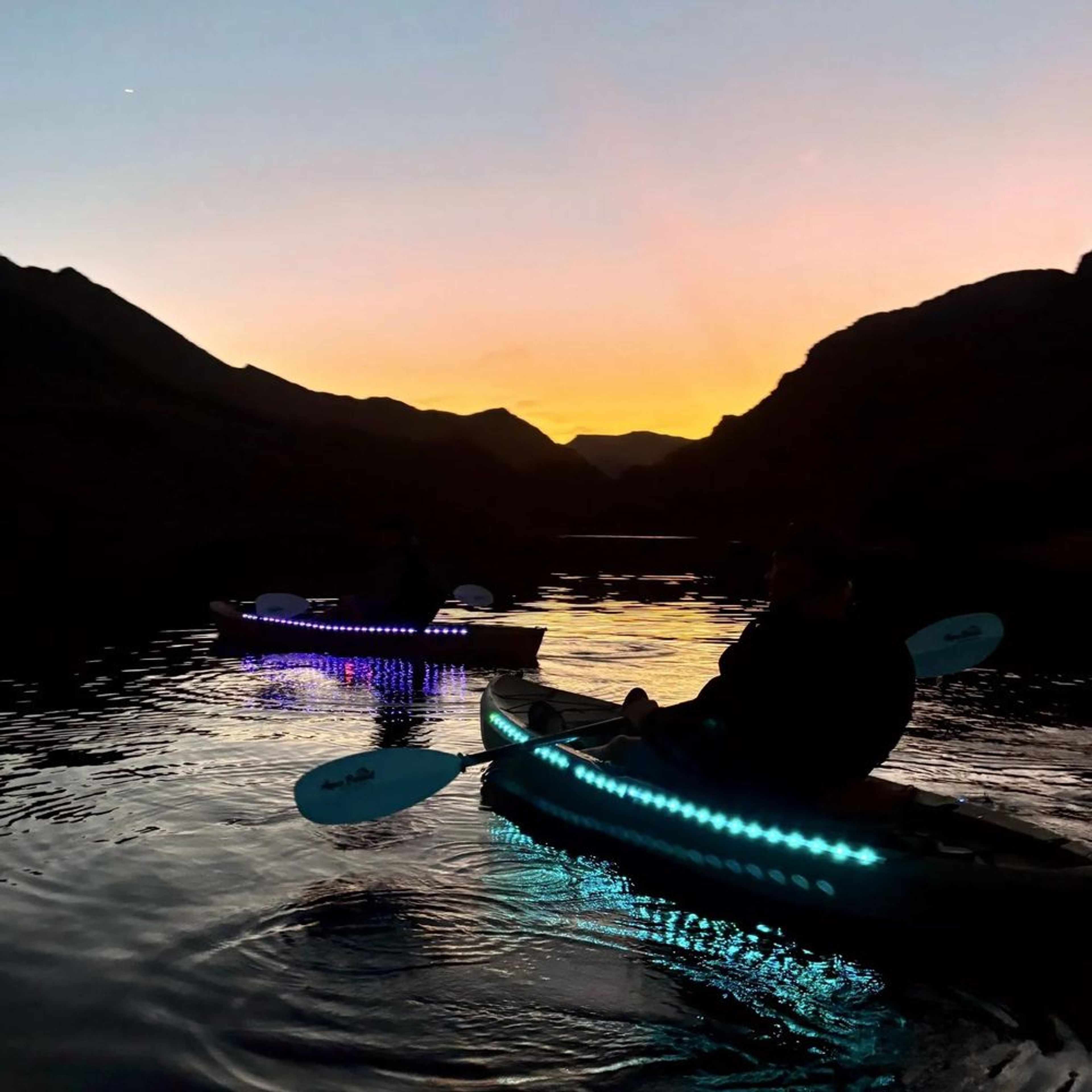 Guests enjoying the sunset and moonrise in glowing kayaks on a full moon tour near Las Vegas