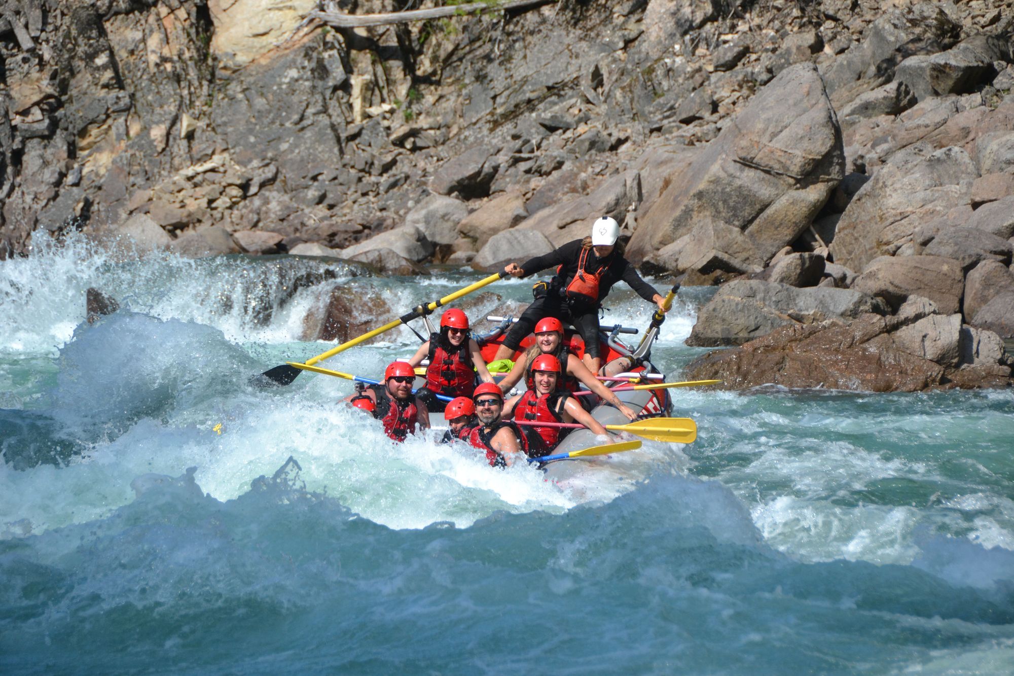 Family of rafters dipping into a big wave in bright blue water of the Clearwater River
