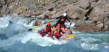 Family of rafters dipping into a big wave in bright blue water of the Clearwater River