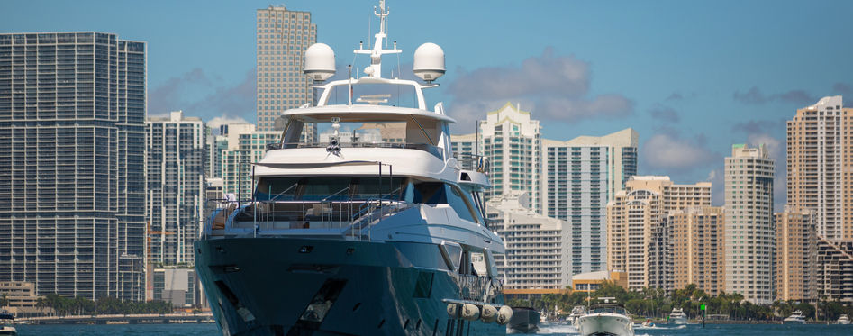 Luxurious yacht cruising on the turquoise waters of Biscayne Bay with the Miami skyline in the backdrop.