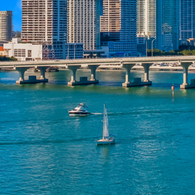 Vibrant Miami skyline viewed from the water with clear skies and calm seas, highlighting the city's bustling waterfront.