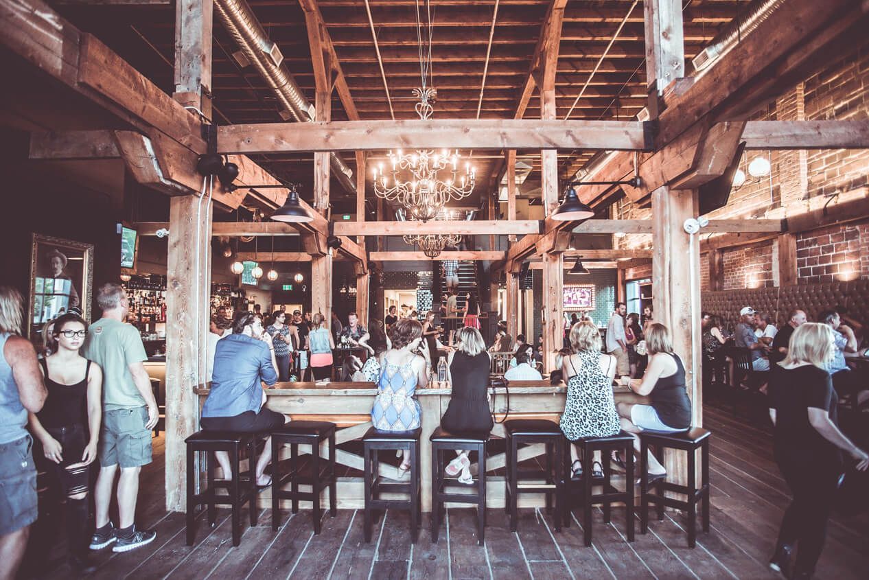 People sitting at the bar at BNA brewery visiting Kelowna
