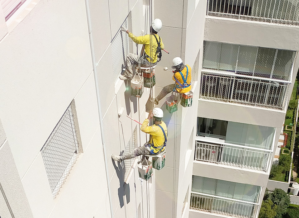 Imagem de 3 trabalhadores realizando pintura predial.