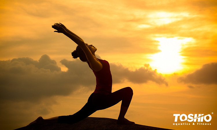 mulher praticando Yoga ao por-do-sol