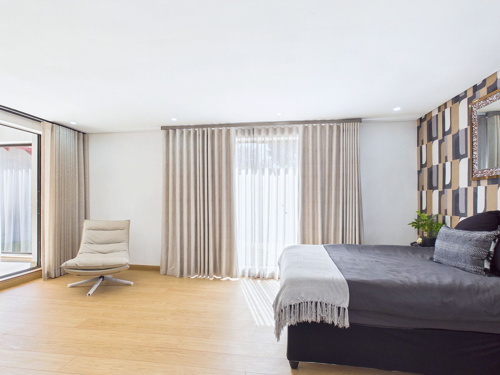 A bedroom dressed with soft taupe wave-heading curtains